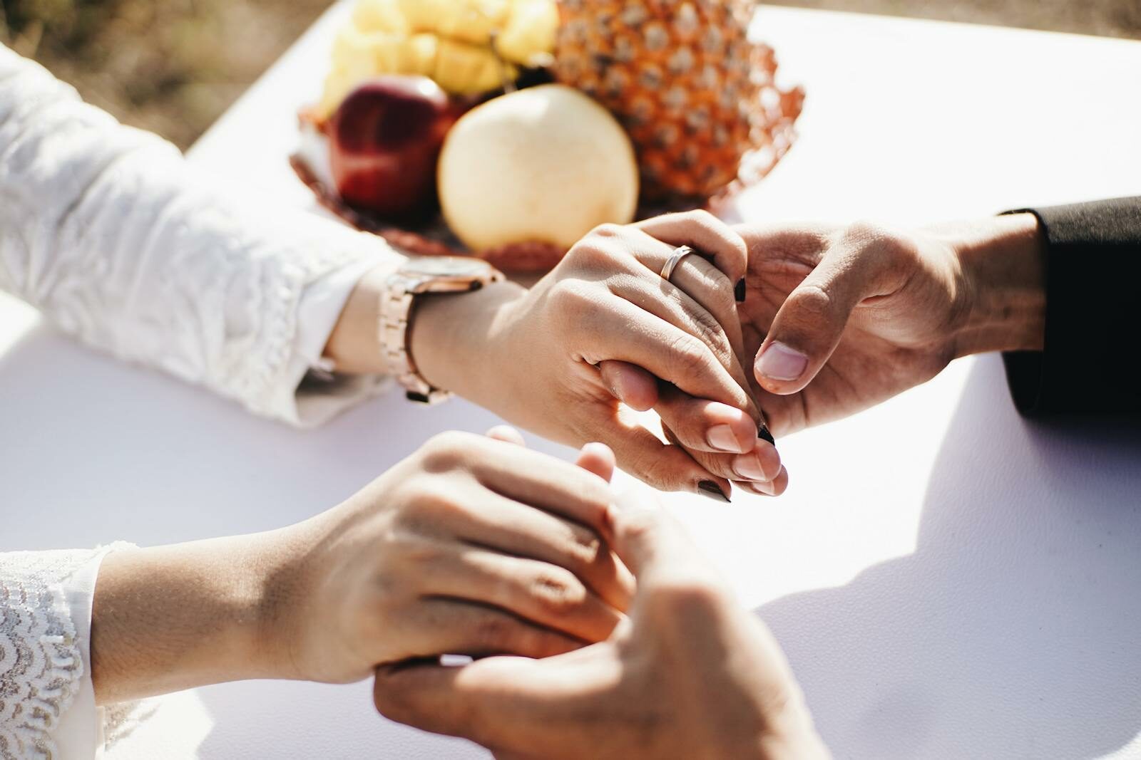 Close-up of a couple holding hands outdoors with fruits nearby, conveying love and affection.
